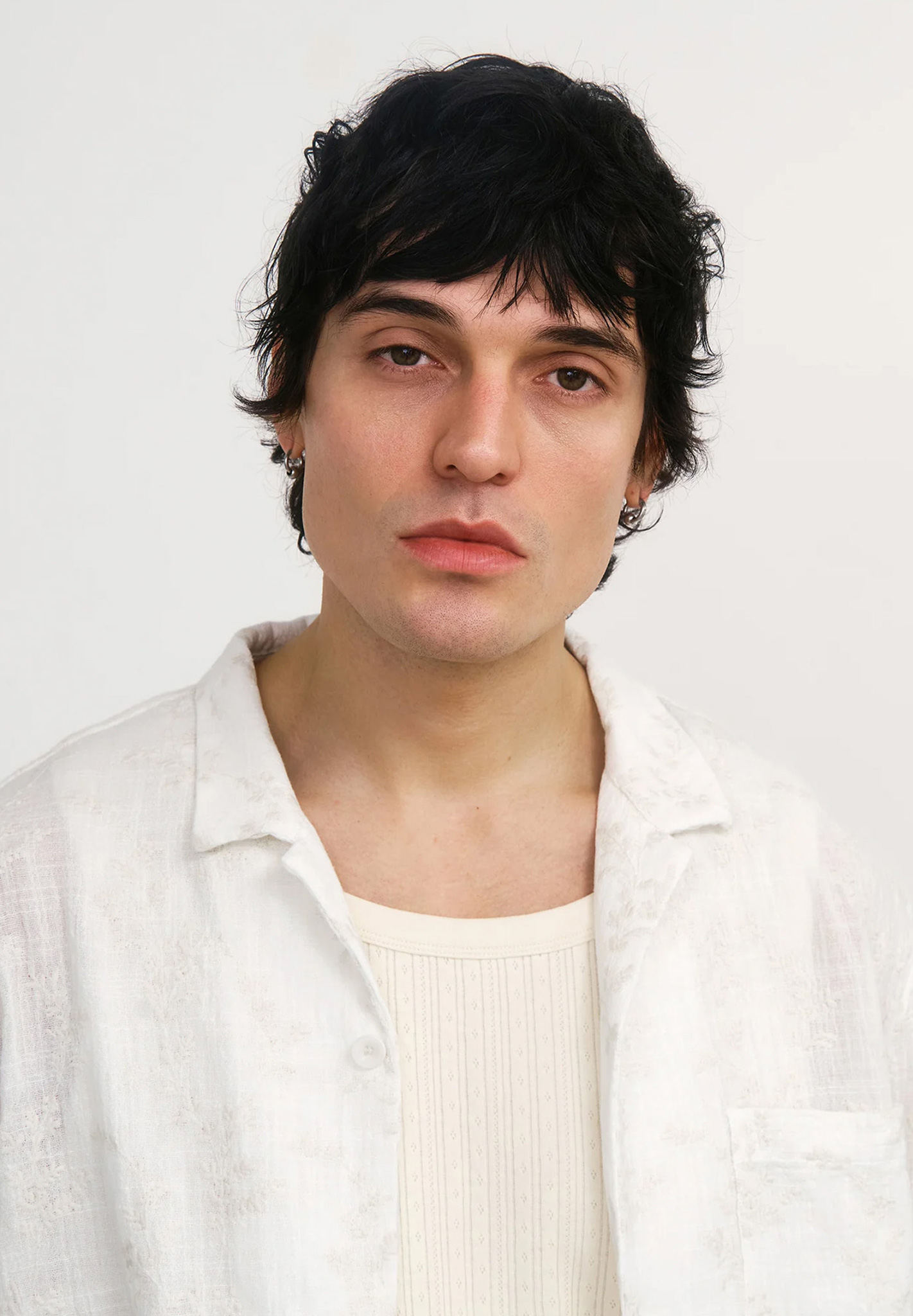 haarfarbe: schwarz, kurzes haar, männergesicht, weißes hemd, lederohrring